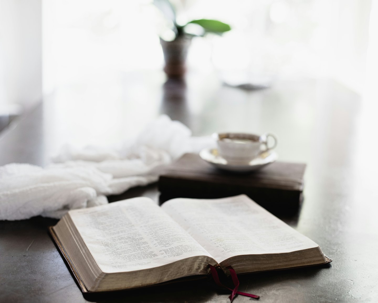 An open book and teacup rest on a table.