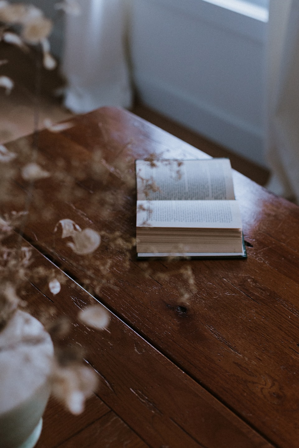 An open book lies on a rustic wooden table.