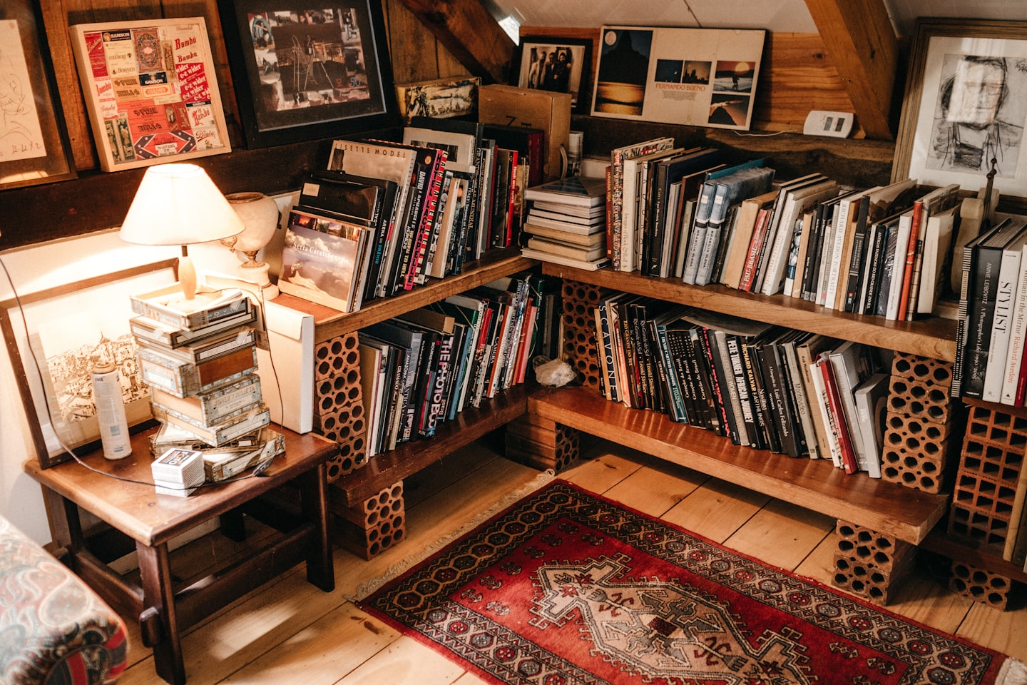 Cozy home study with bookshelves, art, and a lamp.