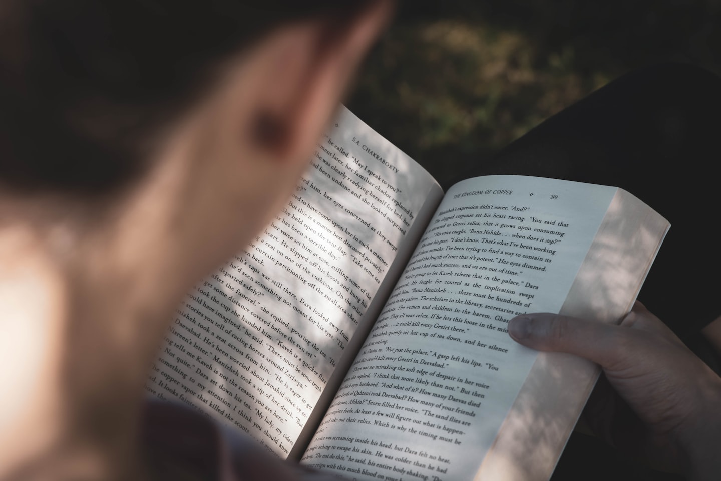 Hands holding open a book with visible text.