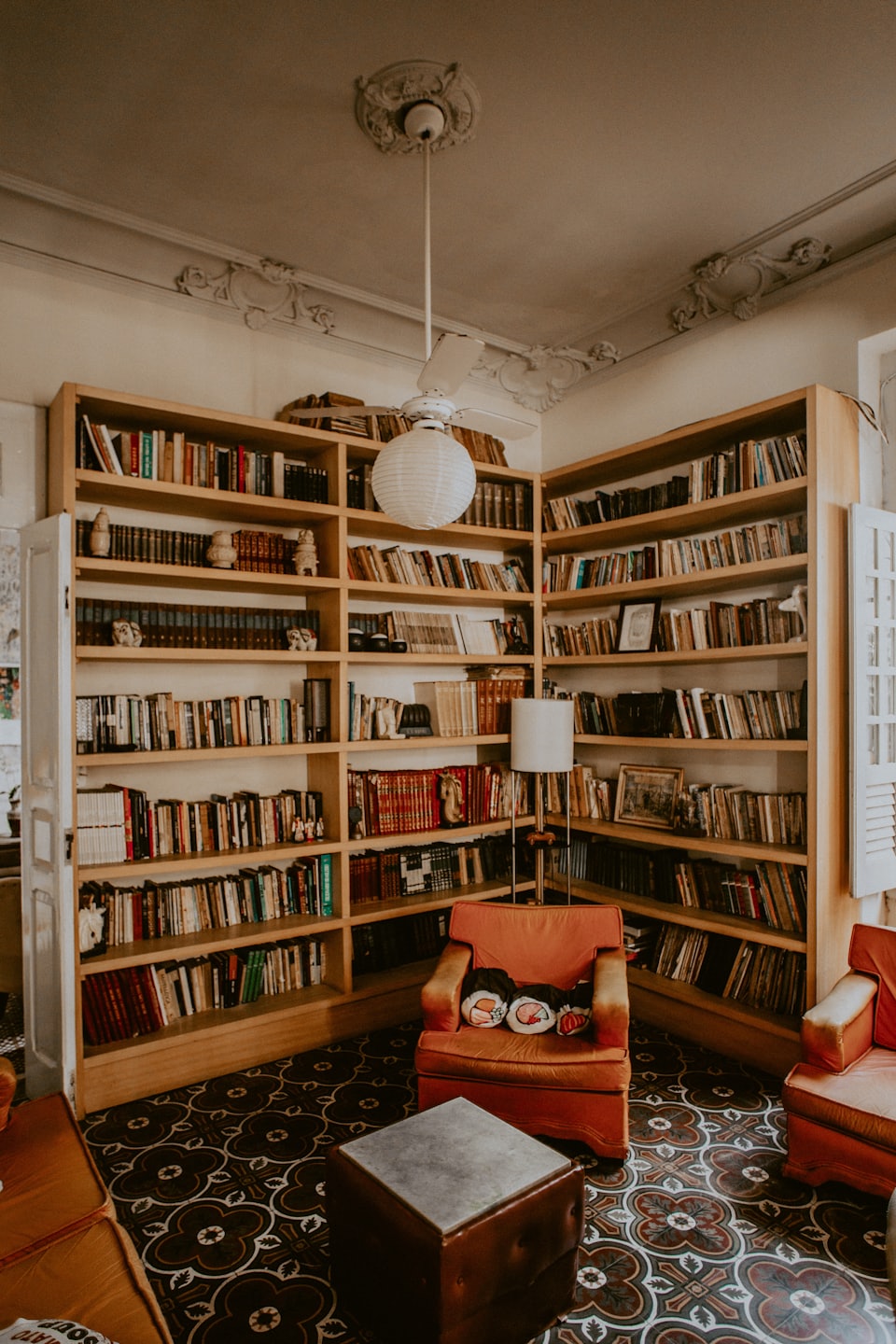 Cozy reading room with two large bookshelves and an orange armchair.